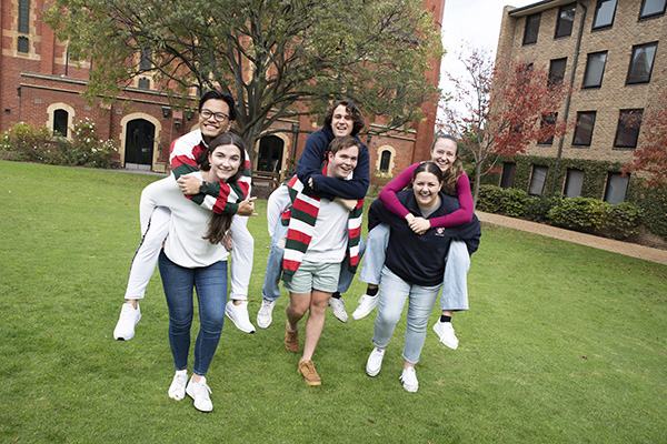 A group of Trinity students giving one another a piggyback on the Bulpadock.