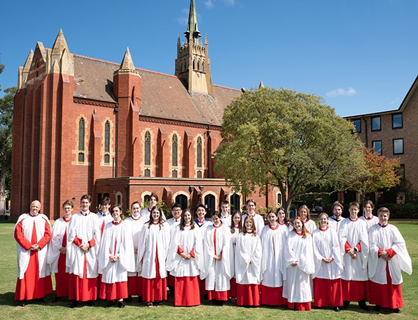 The Trinity College Choir standing on the Bulpadock in their white gowns and red bottoms