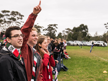 Candid picture of a group of kids cheering on Trinity from the sidelines in one of the intercollegiate sports events.