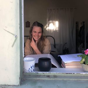 Julia Thwaites looking through an open window, smiling at the camera