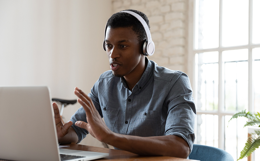 Man with headphones talking at laptop screen