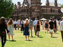 Candid picture of the Trinity College main building with a bunch of people walking towards it across the Bulpadock.