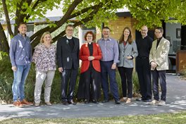 The staff members of Trinity College Theological School are posing for the camera in front of the Old Warden's Lodge.