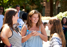 A candid image of three girls talking amongst each other on college grounds.