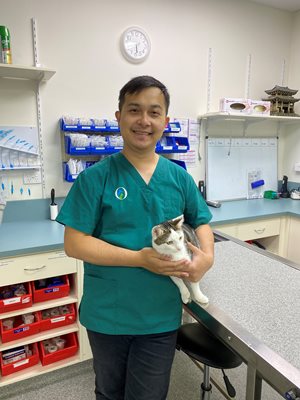 Zhan Hong Lee in a green vet uniform holding a cat